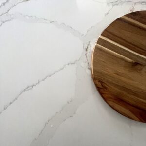 Marble countertop with wooden cutting board on Carrara Golden surface.