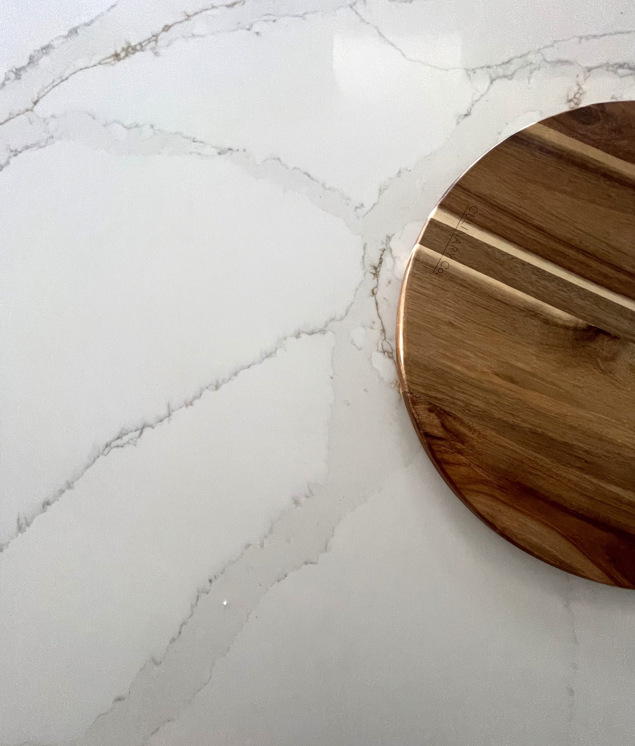 Marble countertop with wooden cutting board on Carrara Golden surface.
