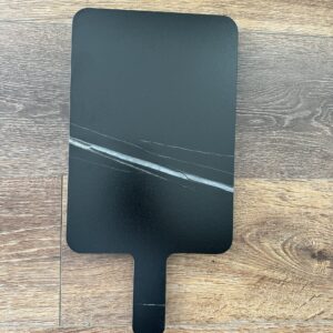 Black marble cutting board on wooden surface.