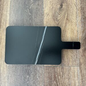Black marble cutting board on wooden floor.