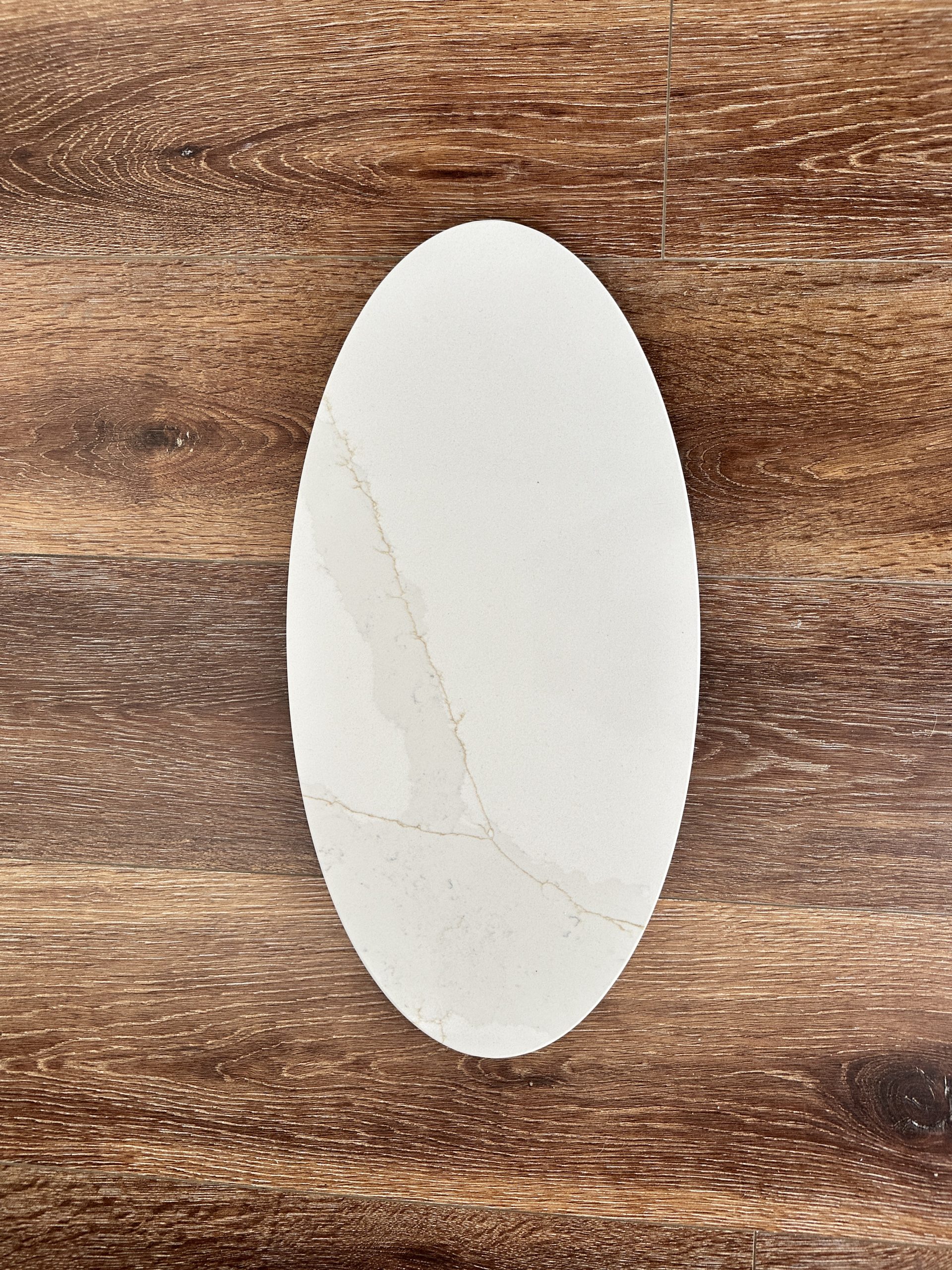 Oval marble plate on wooden table background.