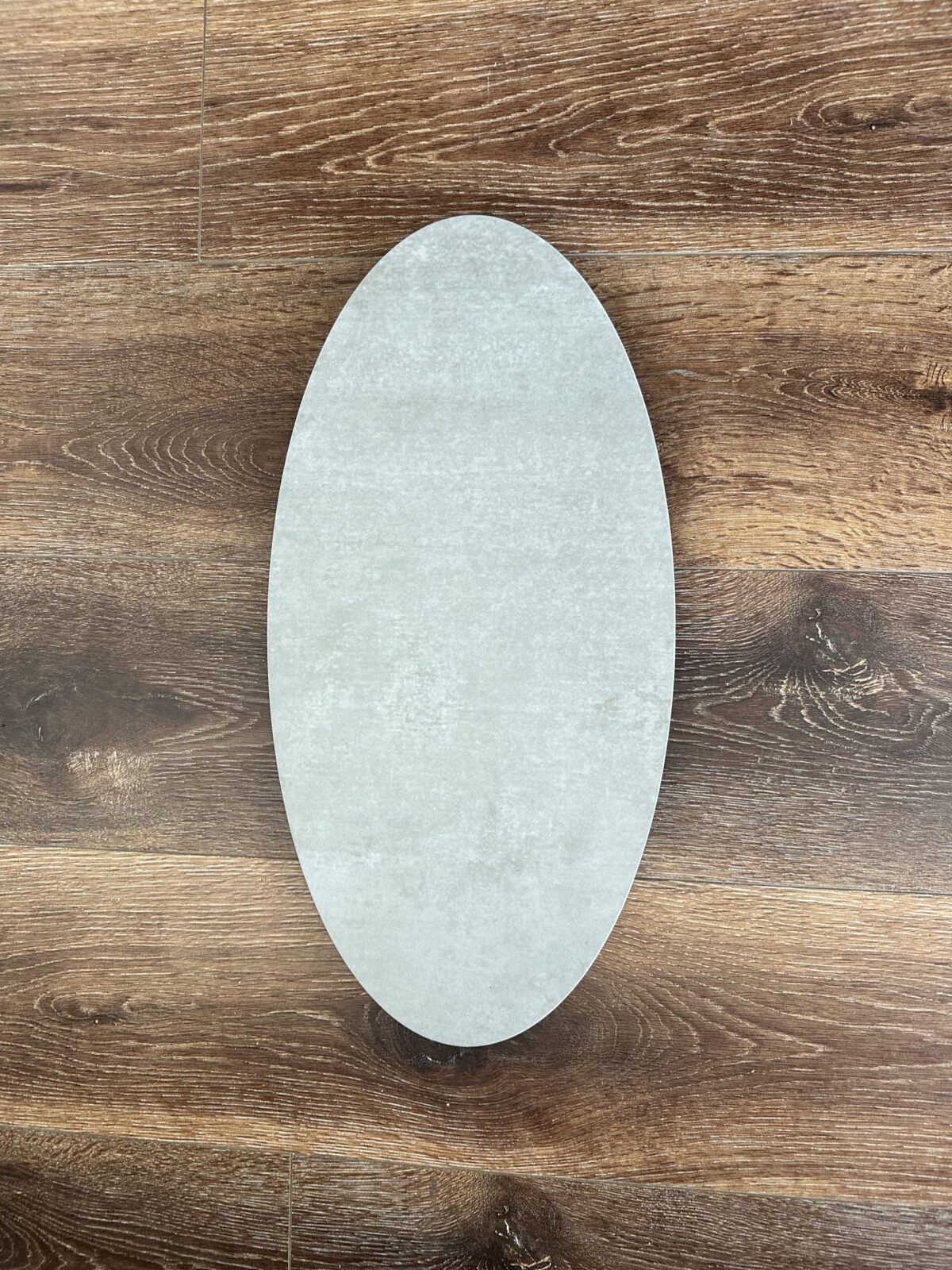 Oval-shaped ceramic plate on wooden floor background.