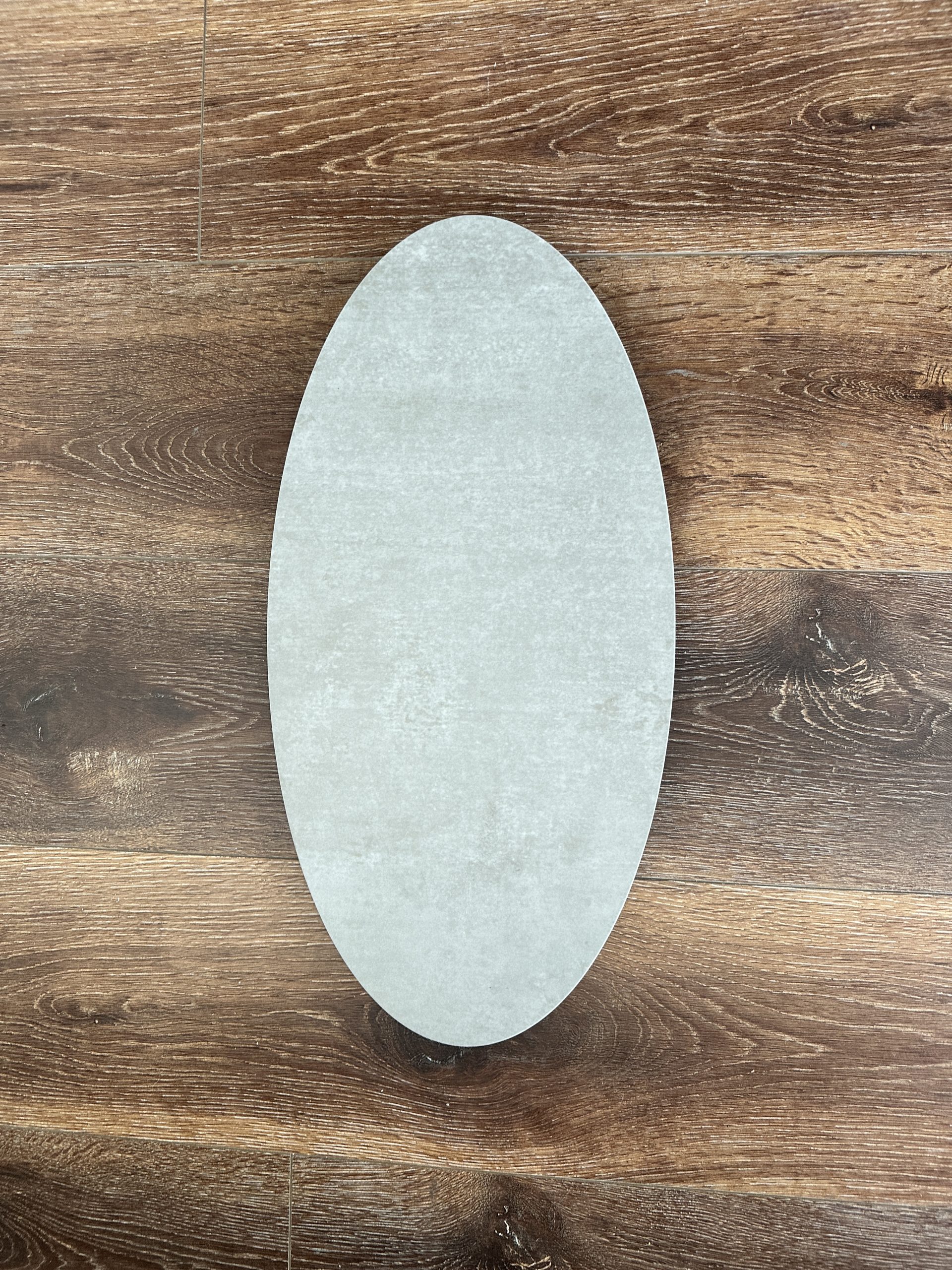 Oval-shaped ceramic plate on wooden floor background.