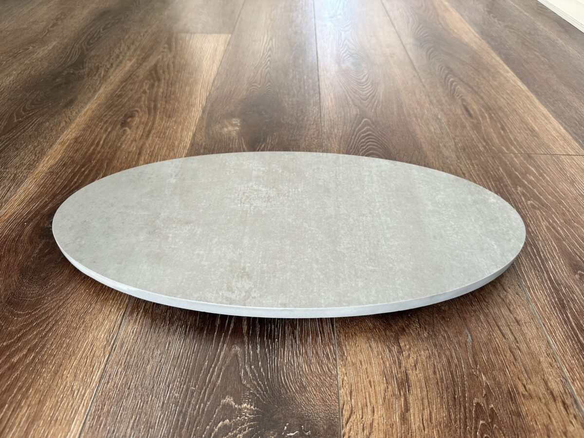 Round stone pizza oven base on wooden floor.