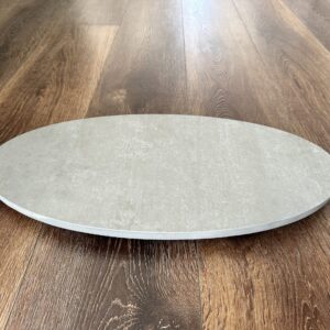 Round stone pizza oven base on wooden floor.