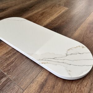 Marble cutting board on wooden kitchen floor.