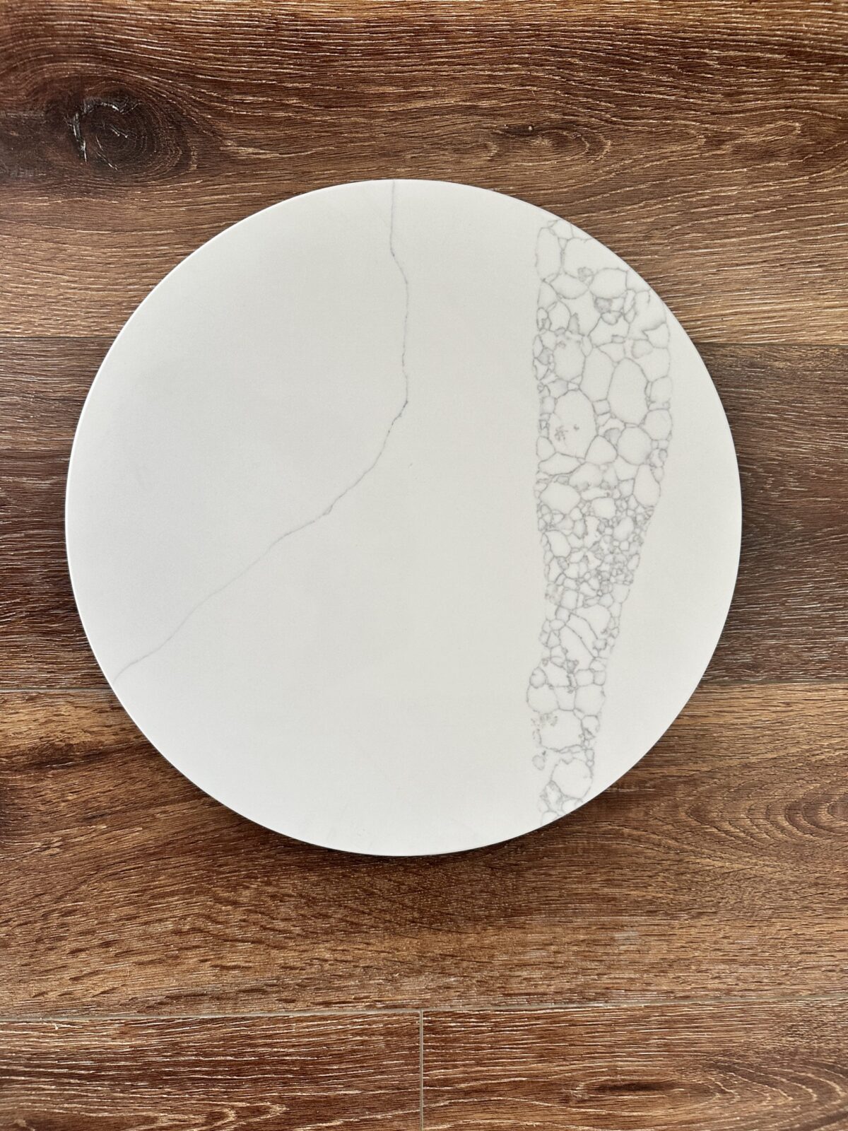 White marble plate with intricate pattern on wooden surface.