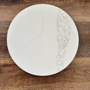 White marble plate with intricate pattern on wooden surface.