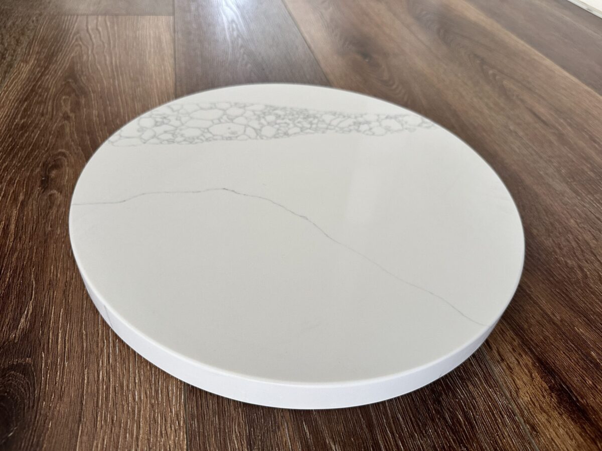 Round marble cutting board on wooden floor.