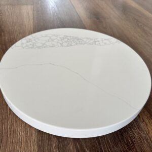 Round marble cutting board on wooden floor.