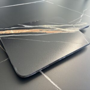 Black marble cutting board with white and brown veining on a matching surface.