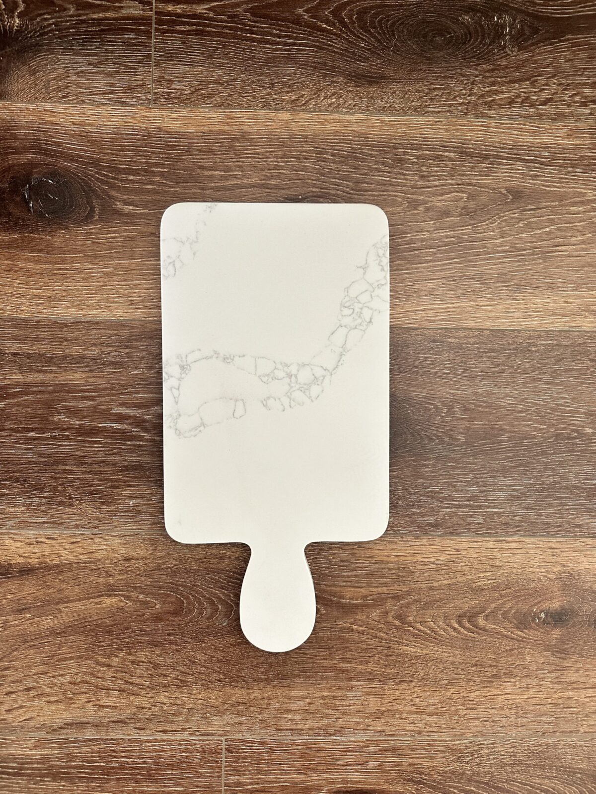 Marble-patterned cutting board on wooden surface.
