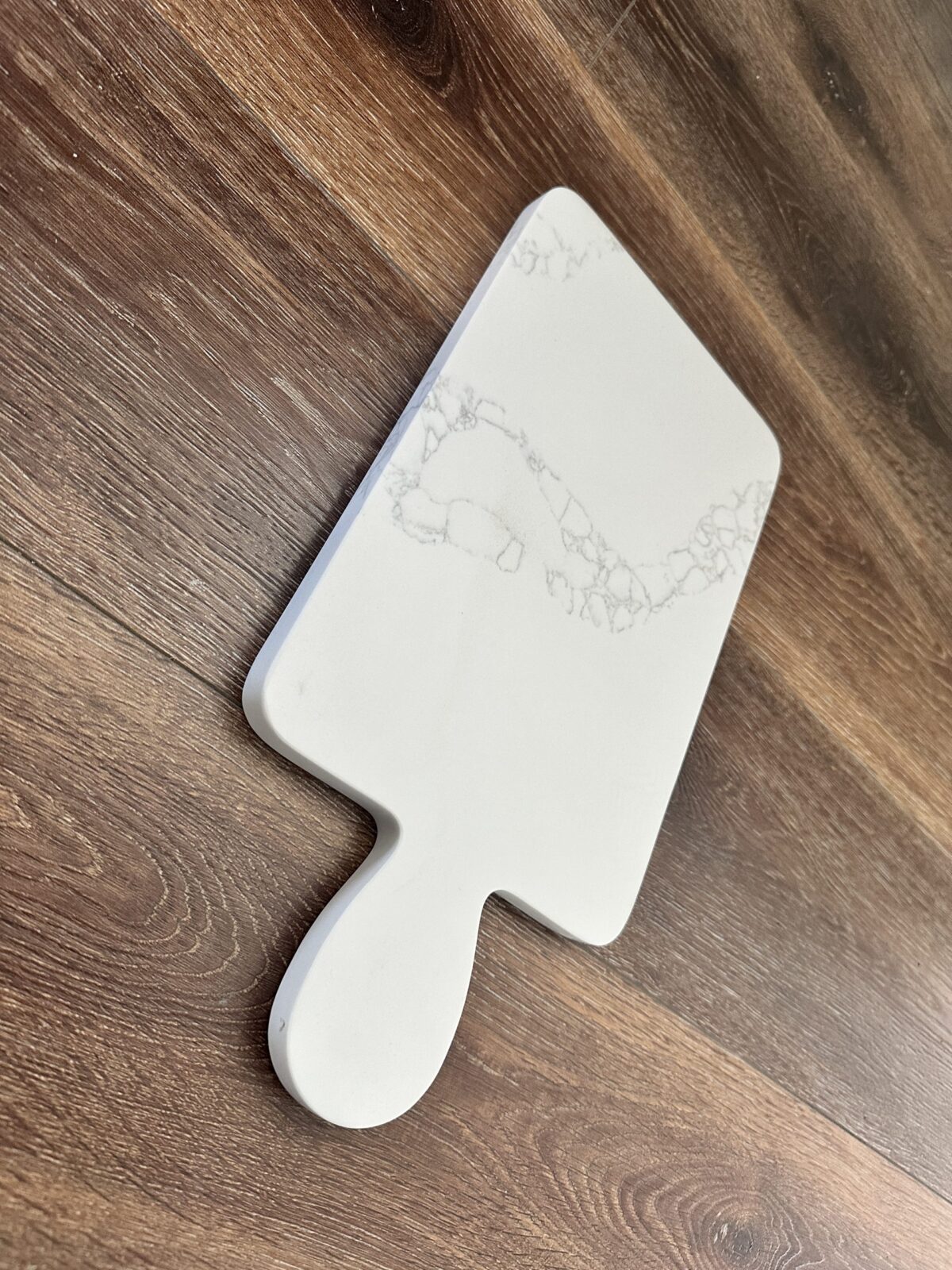 Marble-patterned cutting board on wooden floor.
