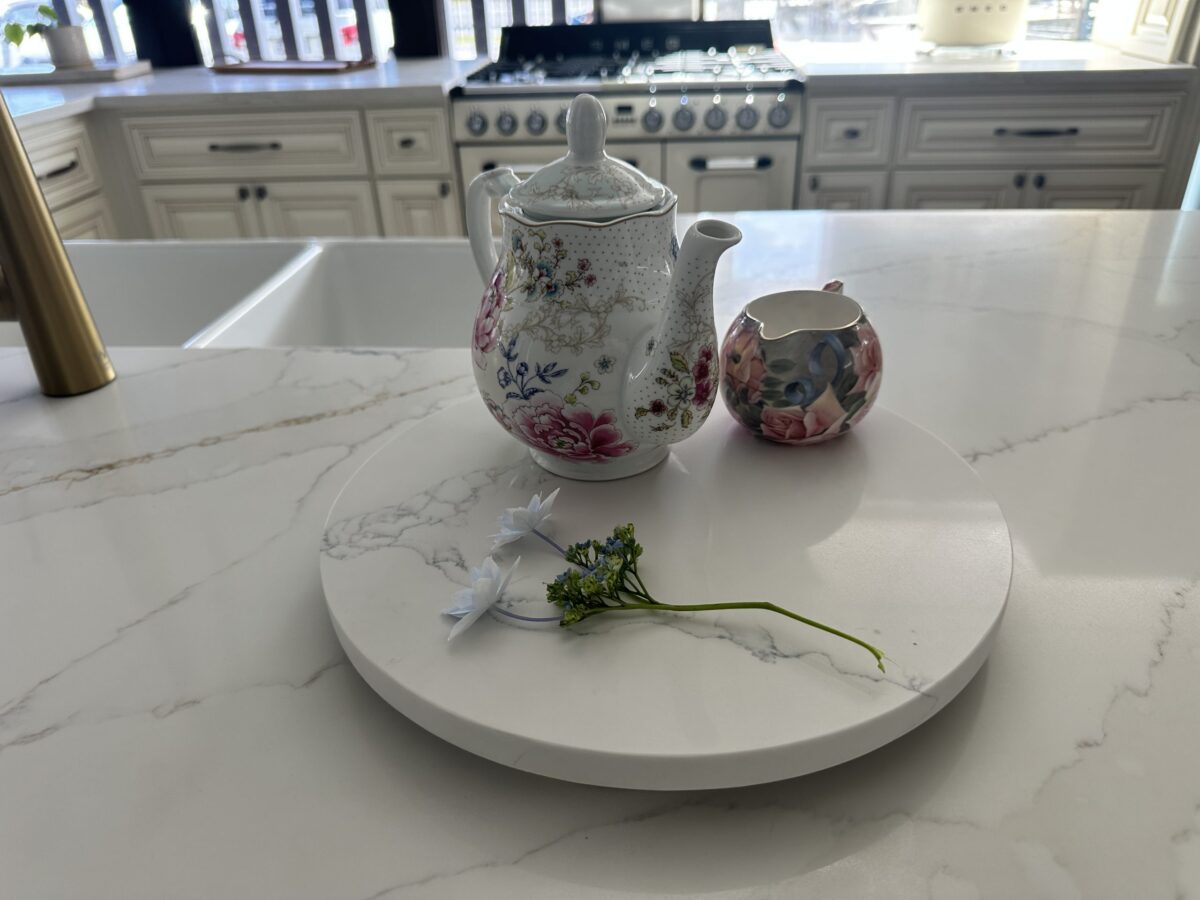 Floral teapot and creamer on marble kitchen counter.