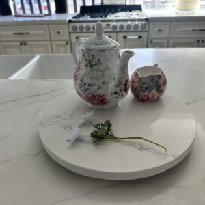 Floral teapot and creamer on marble kitchen counter.
