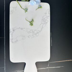 Marble cutting board with blue flowers on a dark surface.