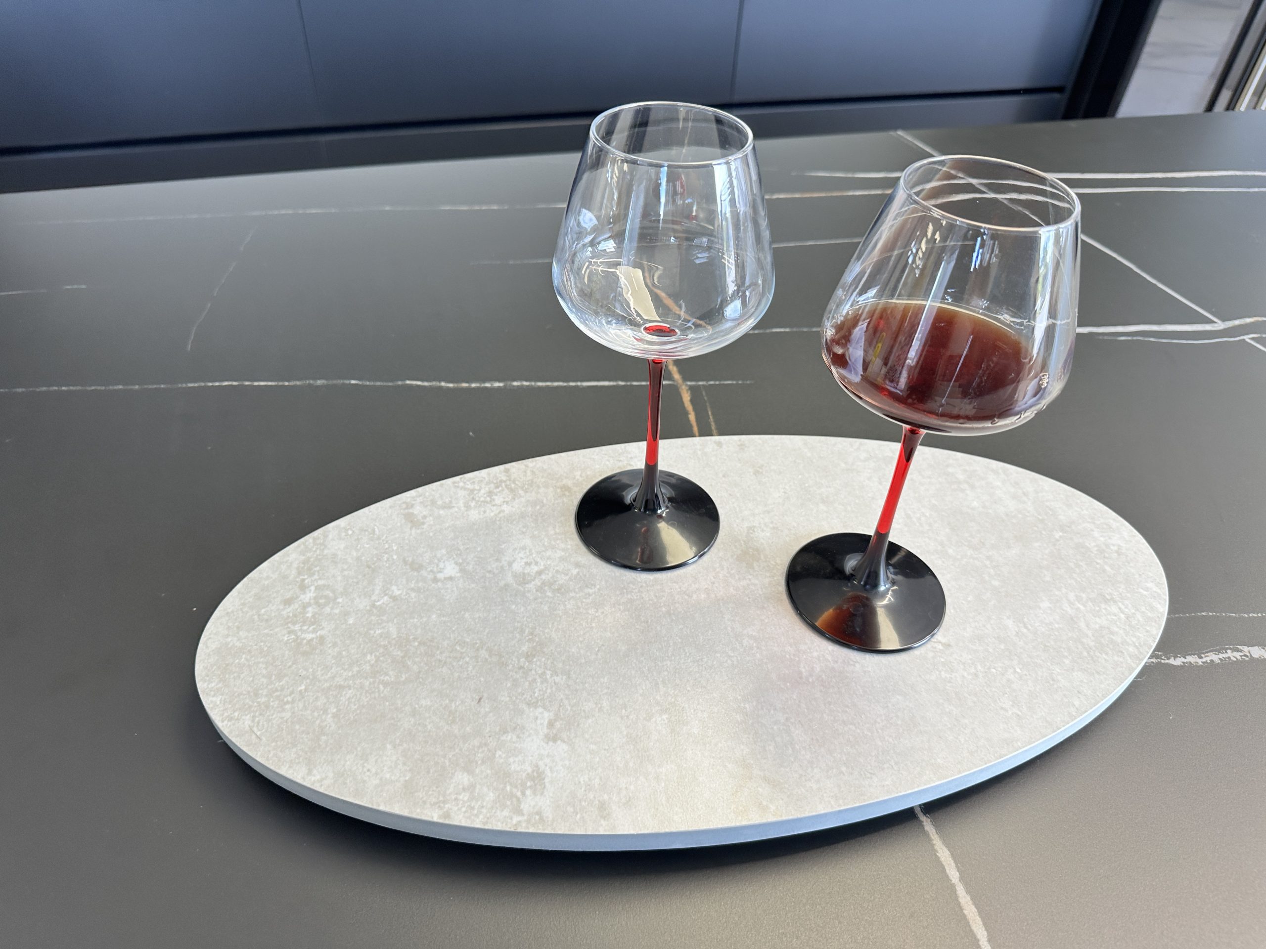 Two wine glasses, one empty, on a modern kitchen countertop.