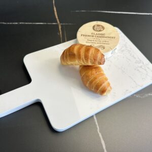 Two croissants and camembert on a marble cutting board.