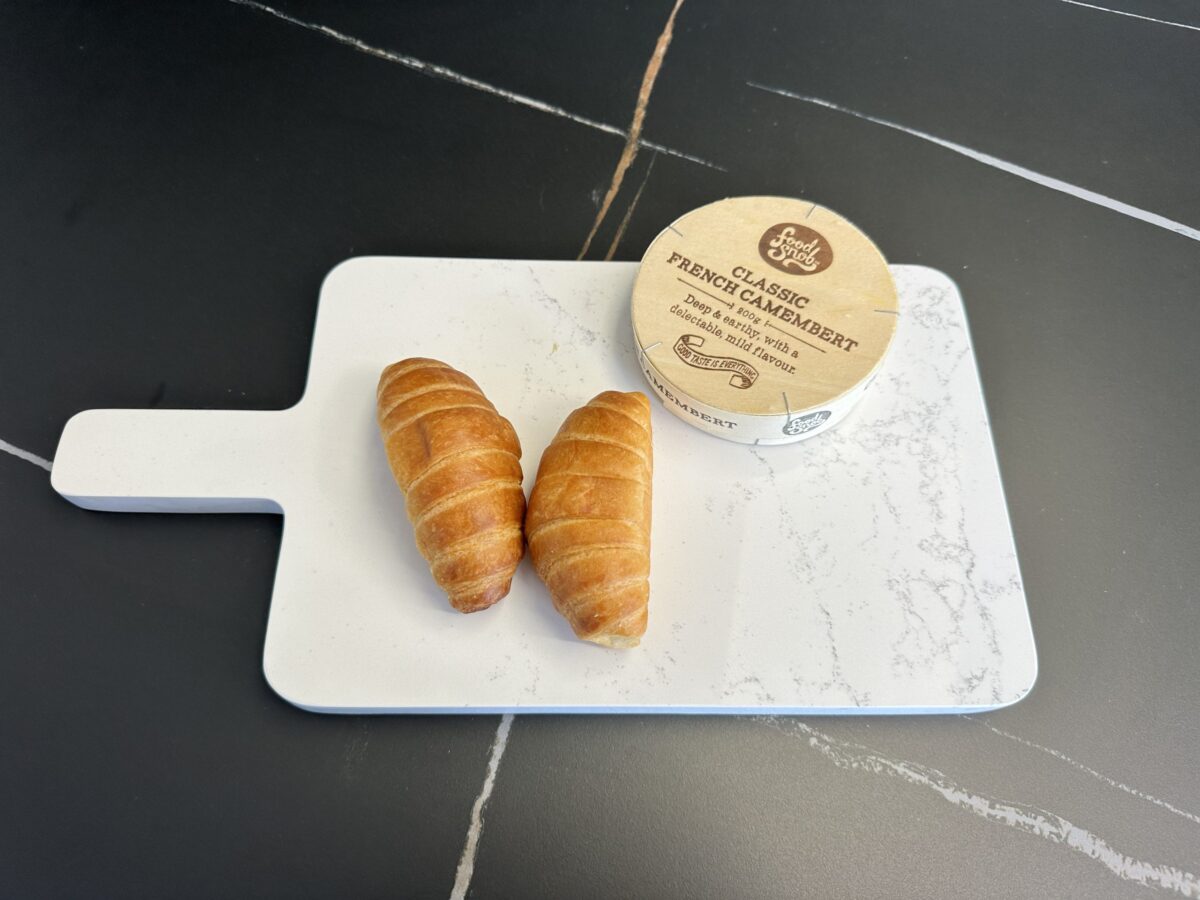 Two croissants and camembert on a marble cutting board.