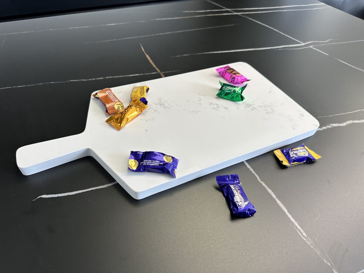 Chocolates on a white cutting board on a dark table.