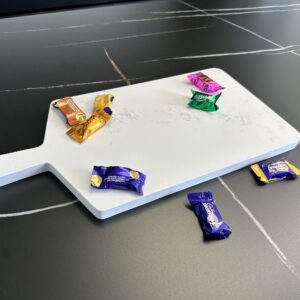 Chocolates on a white cutting board on a dark table.