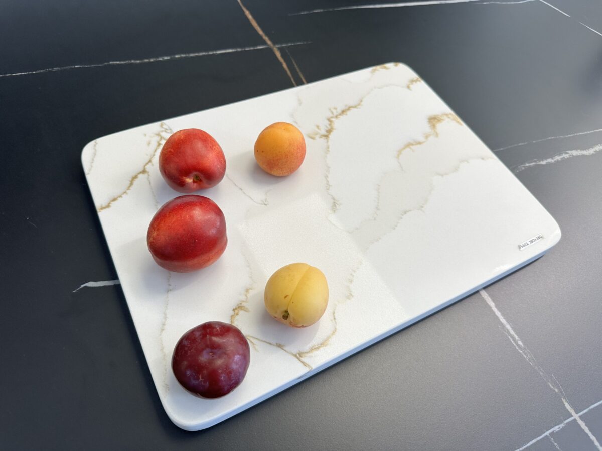 Five assorted fruits on a marble cutting board.