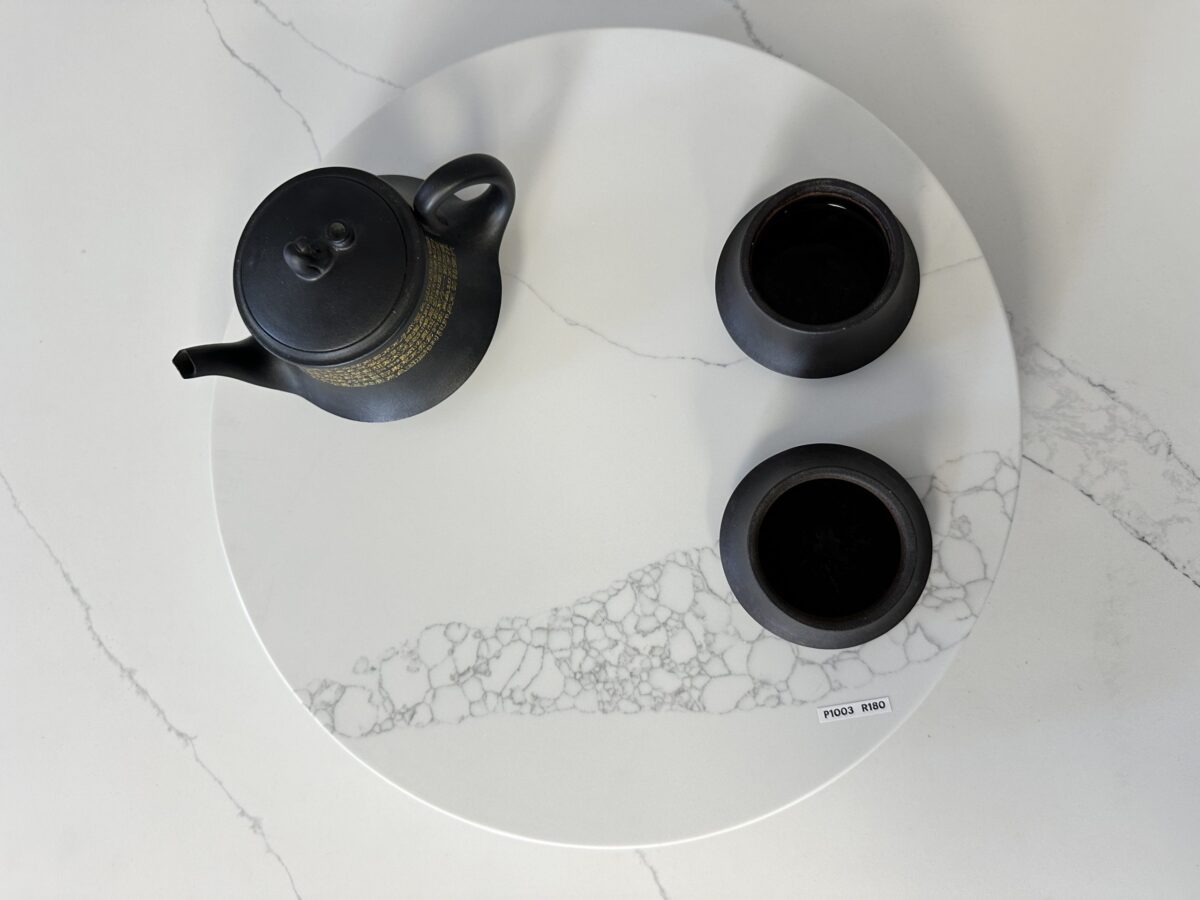 Black teapot and cups on a white marble tray.