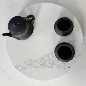 Black teapot and cups on a white marble tray.
