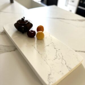 Marble countertop with teapot and three small fruits.