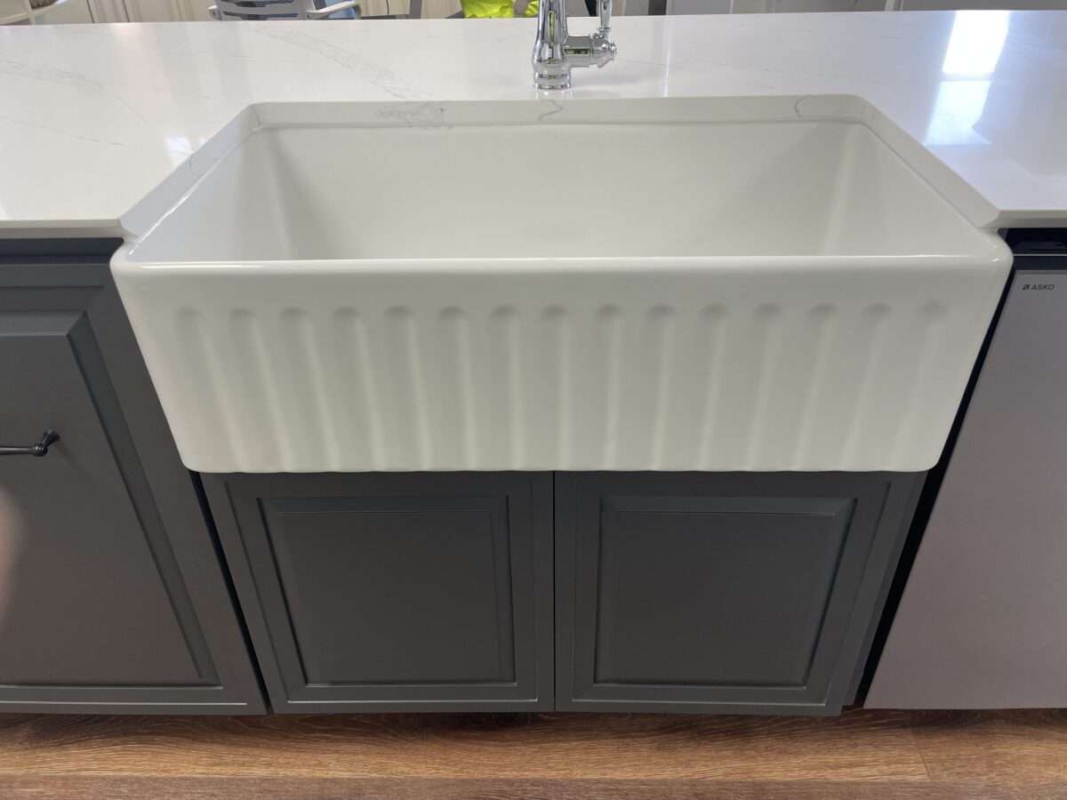 White farmhouse sink with dark cabinets in a modern kitchen.