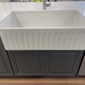 White farmhouse sink with dark cabinets in a modern kitchen.
