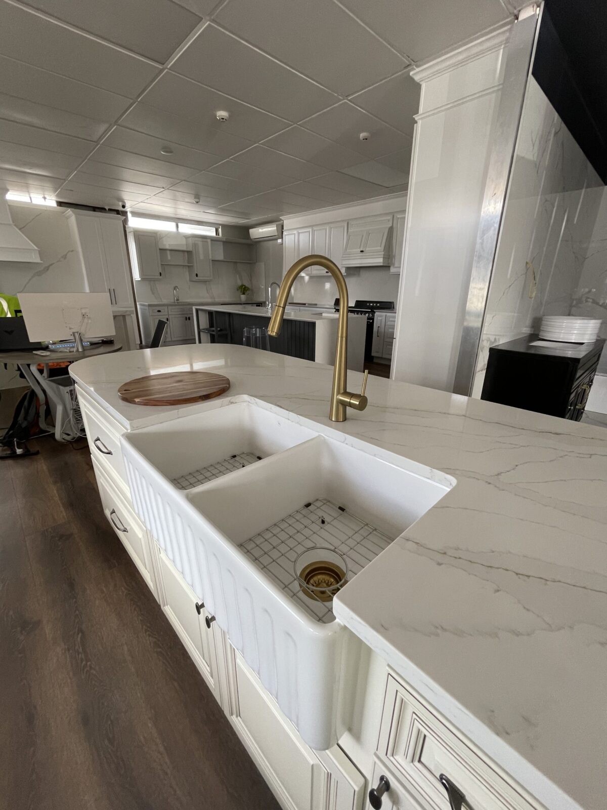Modern kitchen with marble countertops, farmhouse sink, and gold faucet.