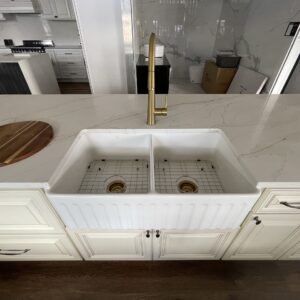 Modern kitchen with marble countertop and double farmhouse sink.