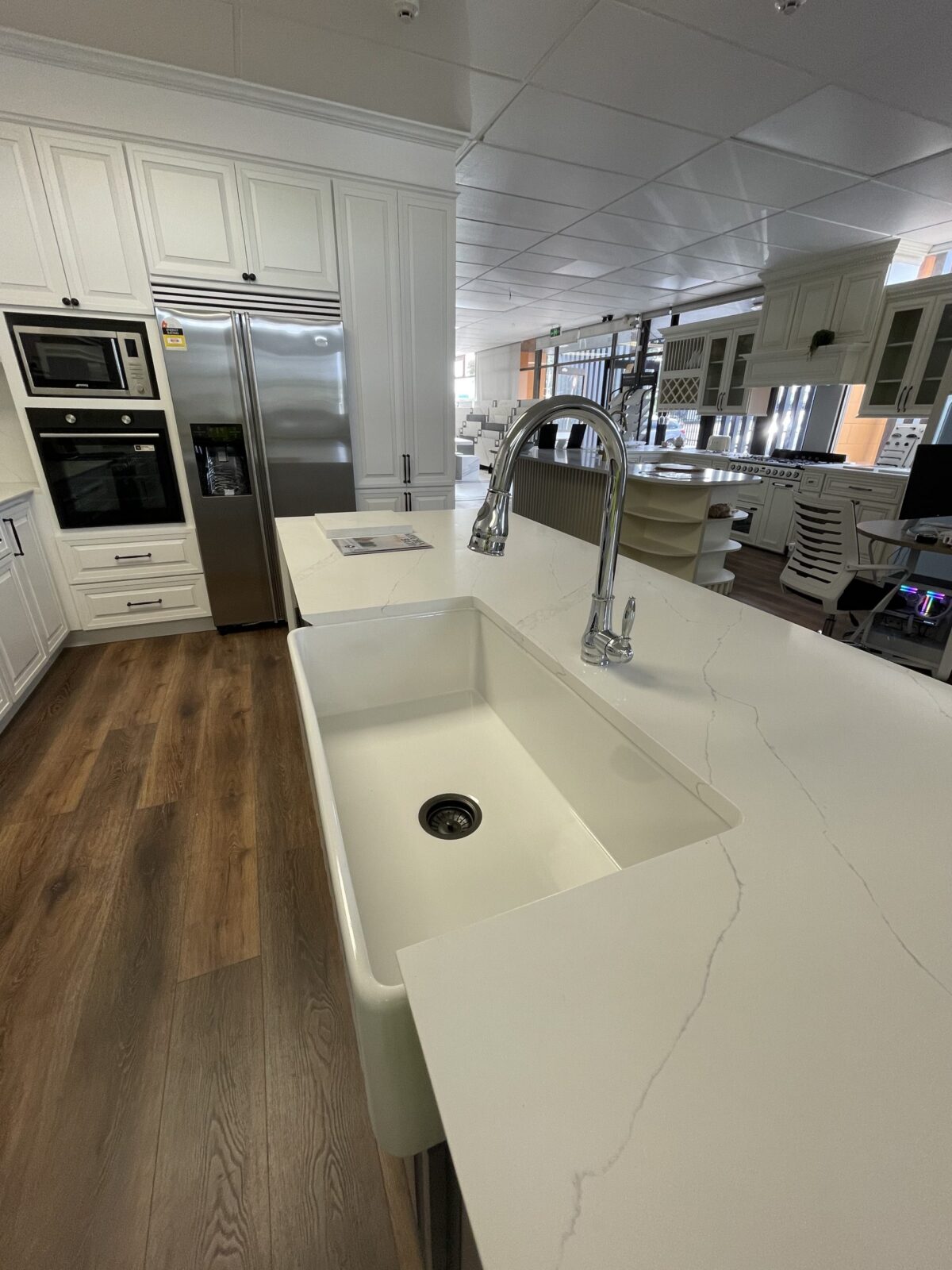 Modern kitchen with white countertops, large sink, and stainless steel appliances.