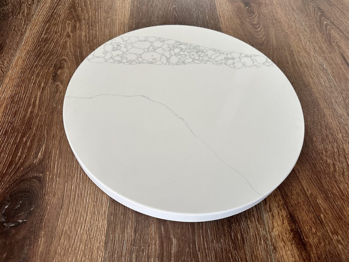 Marble-patterned round serving board on wooden table.