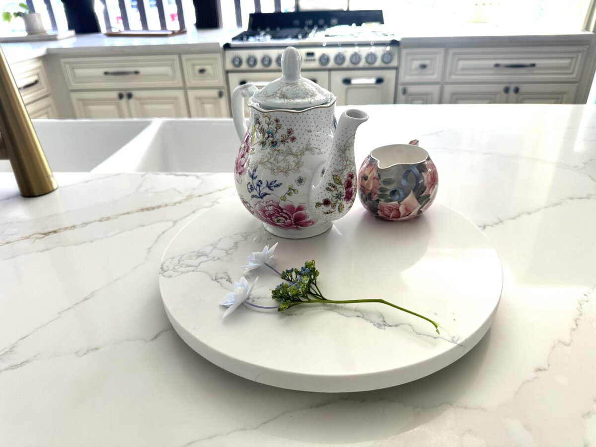 Floral teapot and creamer on marble kitchen counter.