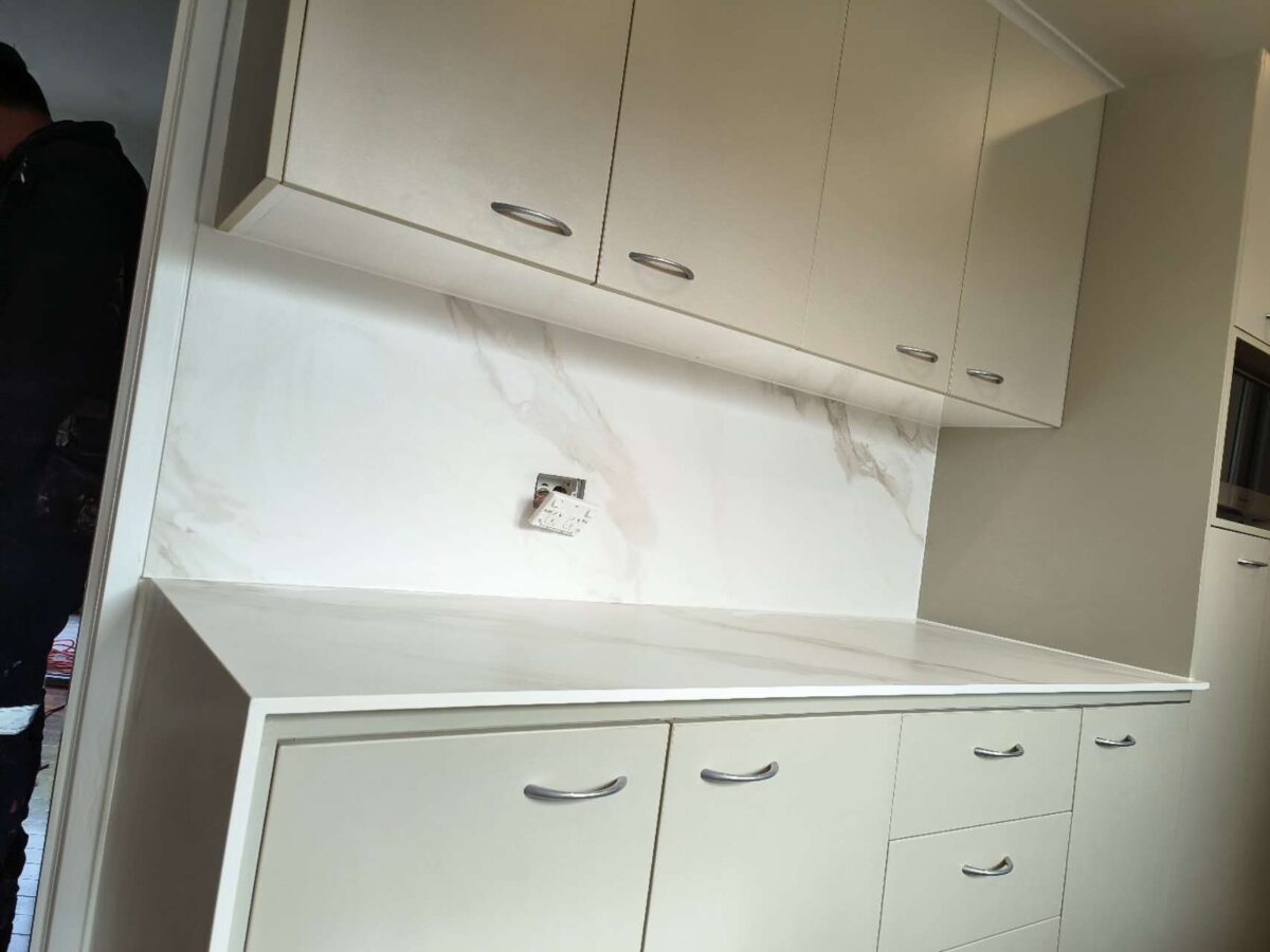 Modern kitchen with white cabinets and marble backsplash.