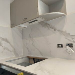 Modern kitchen with marble backsplash and countertop, featuring electrical outlets.