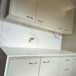Modern kitchen with white cabinets and marble backsplash.