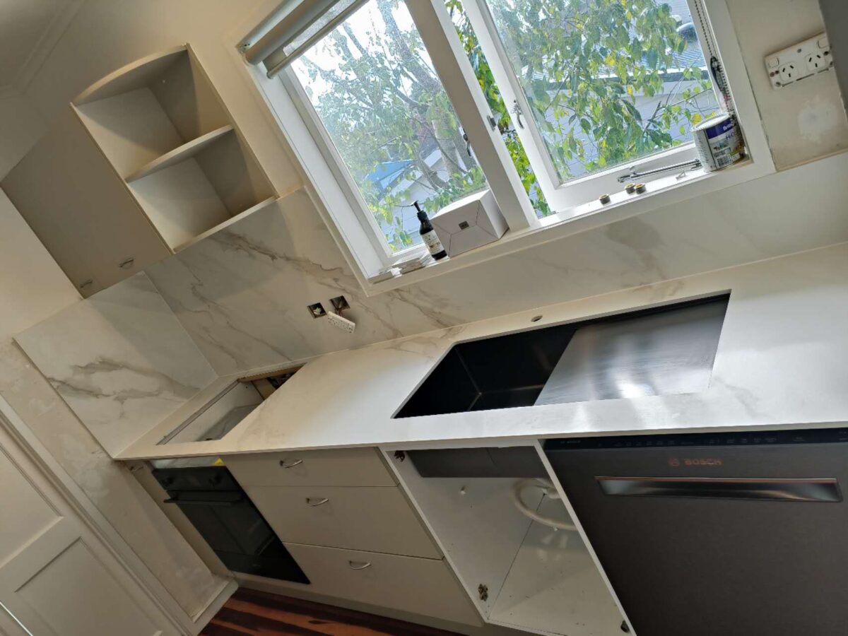 Modern kitchen with marble countertops and stainless steel appliances.