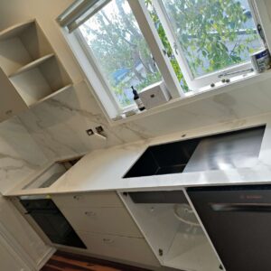 Modern kitchen with marble countertops and stainless steel appliances.