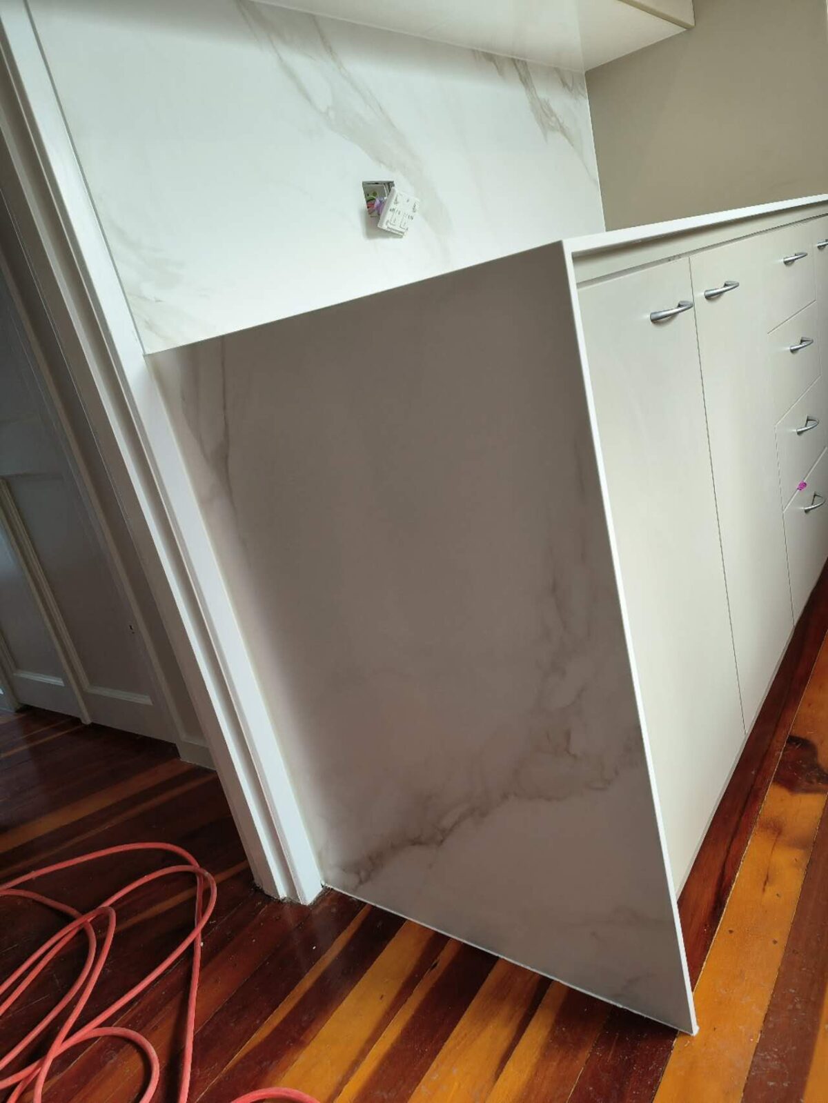 Modern kitchen with marble countertops and white cabinets.