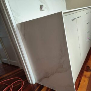Modern kitchen with marble countertops and white cabinets.