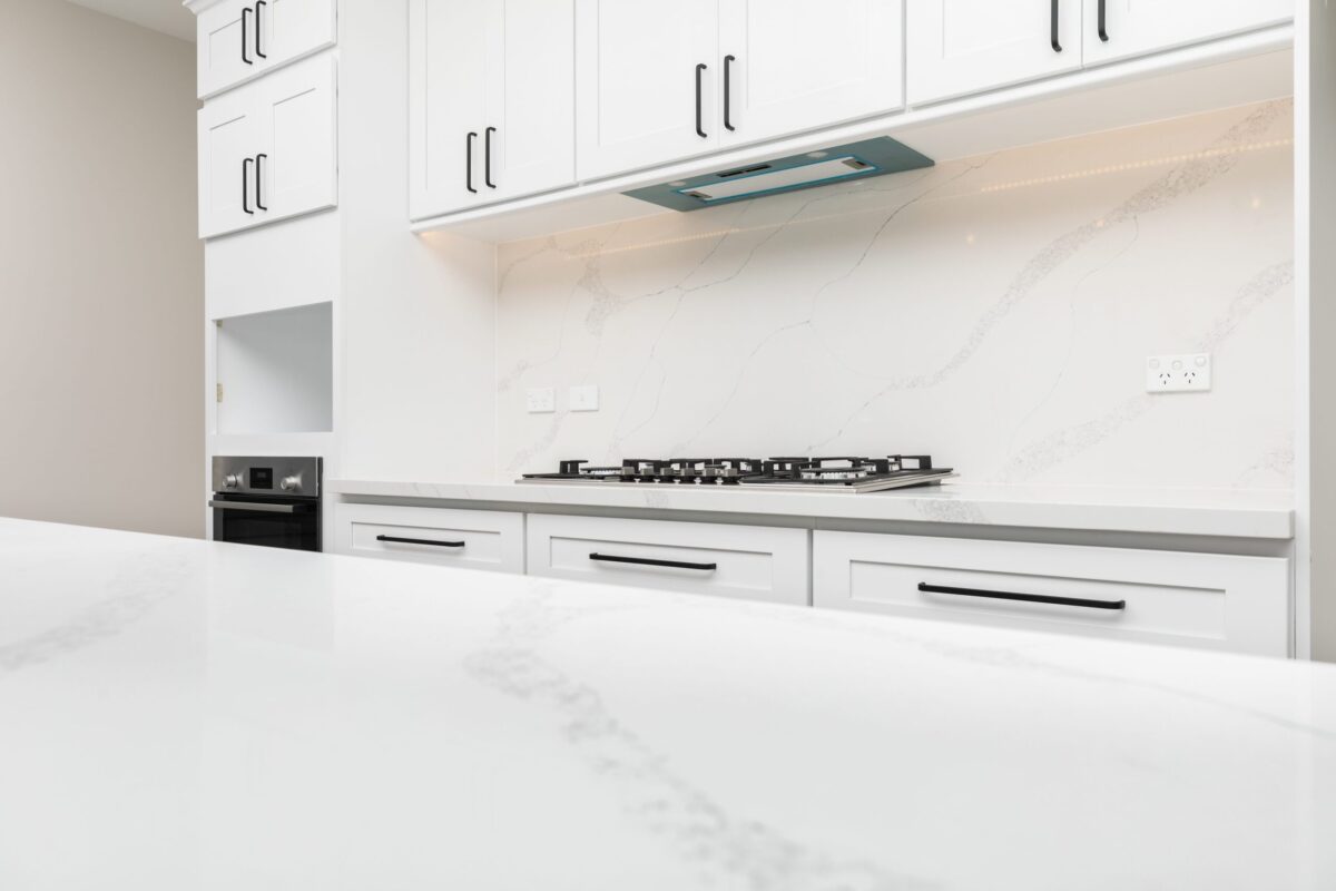 Modern kitchen with white marble countertops and cabinets.