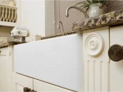Modern white farmhouse sink integrated into traditional kitchen cabinetry with marble countertop