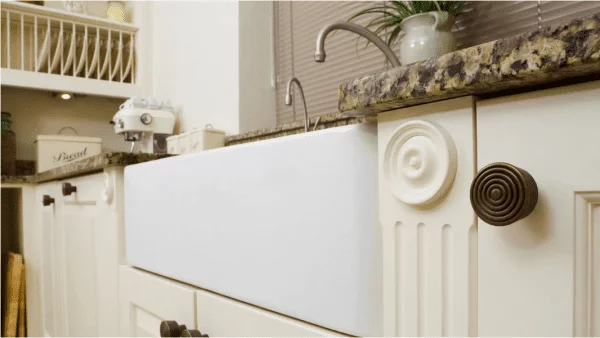 Modern white farmhouse sink integrated into traditional kitchen cabinetry with marble countertop