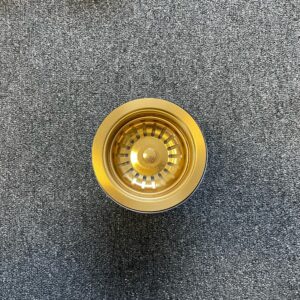 Gold stainless steel strainer on gray carpet, top view.