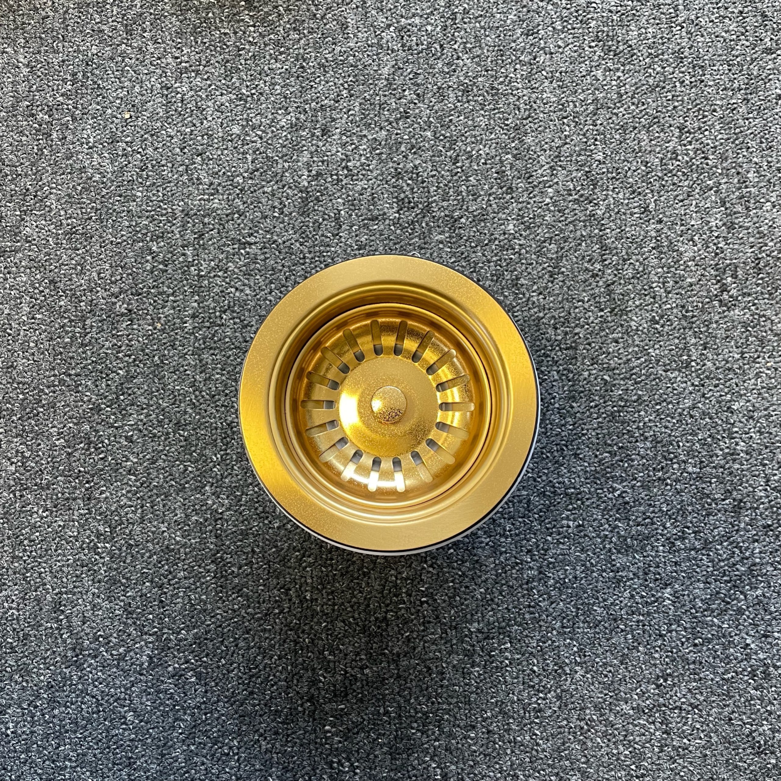 Gold stainless steel strainer on gray carpet, top view.