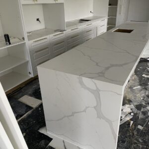Modern kitchen with marble island countertop under construction.