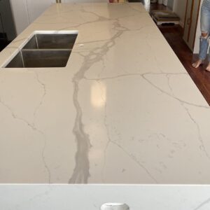 Marble kitchen countertop with sink, person standing nearby.